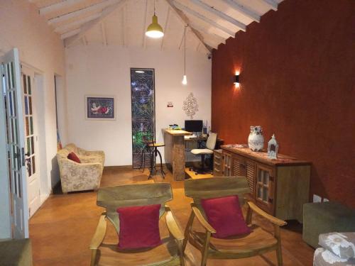 a living room with chairs and a table and a desk at Pousada Cantares in Tiradentes
