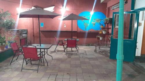 un patio con sillas, mesas y sombrillas en Tu Hostel Tucuman en San Miguel de Tucumán