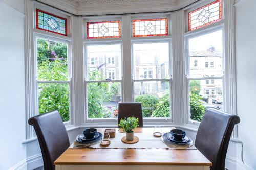a dining room with a table and chairs and windows at April Disc - Long Stay - Contractors in Bristol