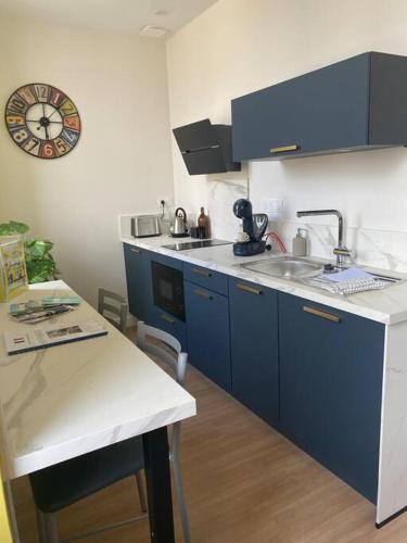 - une cuisine avec des placards bleus, un évier et une horloge dans l'établissement Superbe studio centre ville * clim * WIFI * Haut de gamme *, à Angoulême