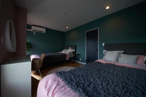 a bedroom with two beds and a green wall at Villacation the Loose in Minamiawaji