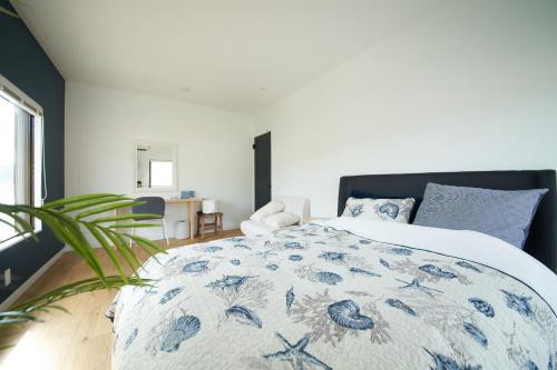 a bedroom with a bed with a blue and white comforter at Villacation the Loose in Minamiawaji