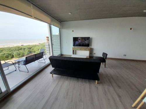 a large living room with a piano and a large window at Northbeach, Pinamar in Costa Esmeralda