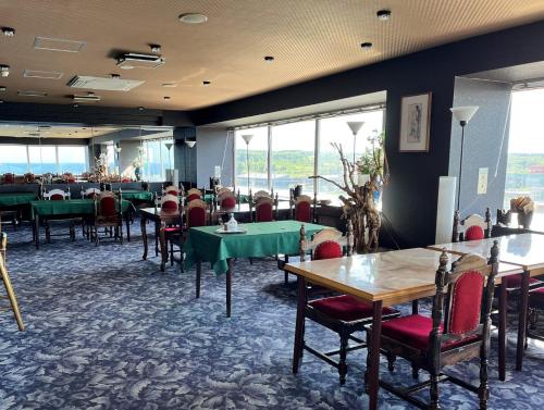 a dining room with tables and chairs and windows at Kitaguni Grand Hotel in Rishirifuji