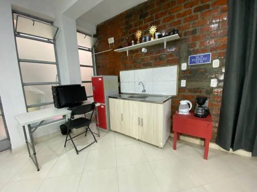 een keuken met een wastafel, een bureau en een bakstenen muur bij Apartment studio fotografico in Huancayo