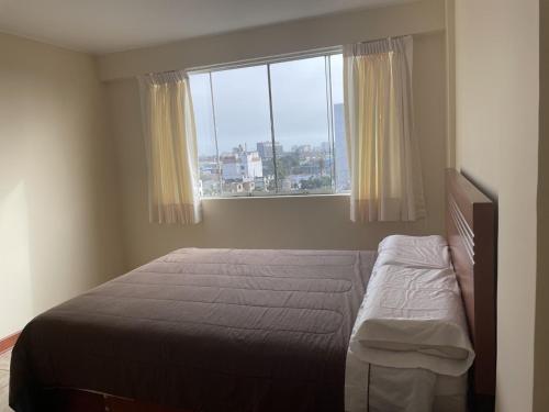 um quarto com uma cama e uma grande janela em santa emma 701 em Lima