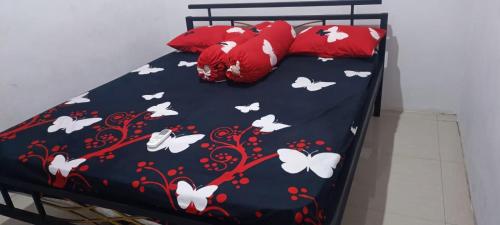 a bed with a black bedspread with white butterflies and red pillows at Villa Omakost3probolinggo in Probolinggo