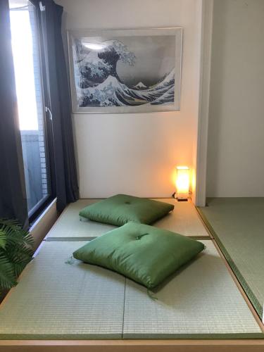 zwei grüne Kissen auf dem Boden in einem Zimmer in der Unterkunft 遊泊天王寺YupaStay in Osaka