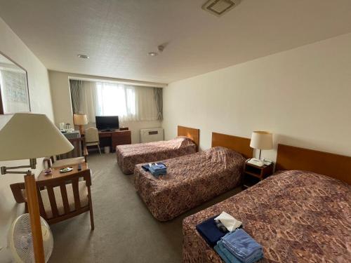 a hotel room with three beds and a desk at Kitaguni Grand Hotel in Rishirifuji