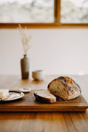 a cutting board with a loaf of bread on a table at Mill Cabin —Luxury Granite Cabin, Mountain views in Crackenback