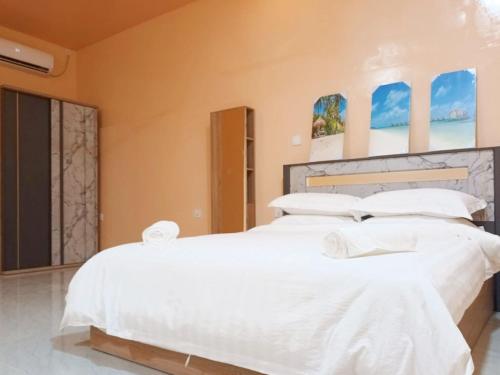 two beds in a bedroom with white sheets and pillows at Tropical stay Thulusdhoo in Thulusdhoo