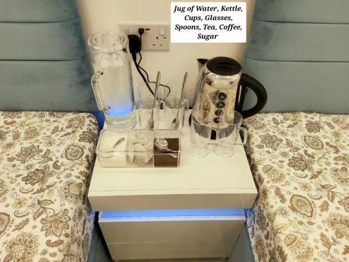 a bed room with a nightstand with glasses on it at Air Conditioned Modern Double Bed Room with Private Attached Bathroom - FREE Parking - Near London Heathrow Airport & Southall Broadway in Southall