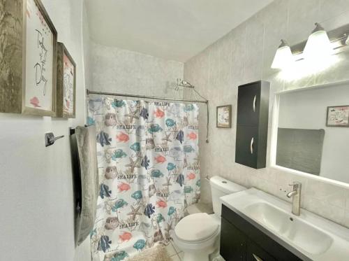 a bathroom with a toilet and a sink and a shower curtain at Oasis Inn in San Juan