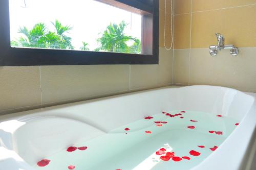 a bath tub with roses on it with a window at Hoi An Lotus Aroma Villa in Hoi An