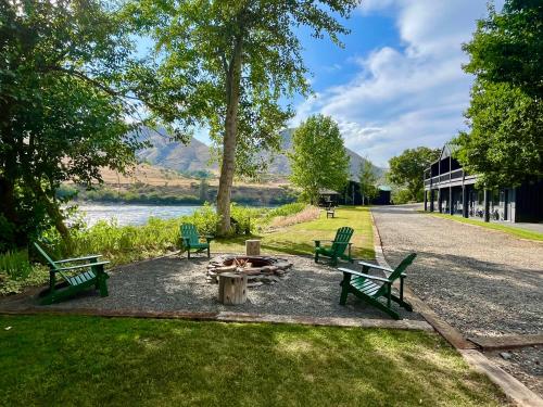 two green benches and a fire pit next to a lake at Steelhead Lodge in Lucile