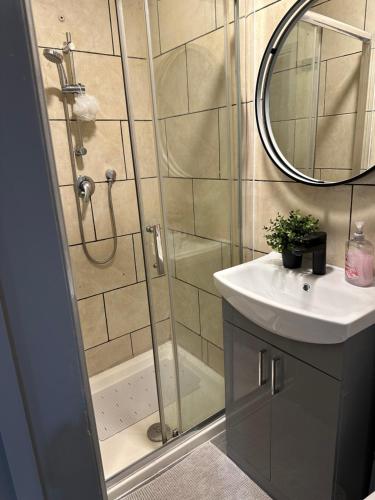 La salle de bains est pourvue d'une douche, d'un lavabo et d'un miroir. dans l'établissement Acton high street, à Londres