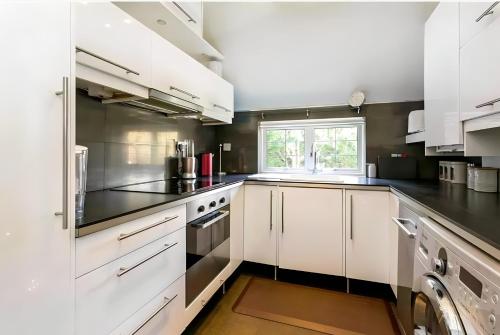 a kitchen with white cabinets and black counter tops at Exclusive Apartment in Greater London in Croxley Green