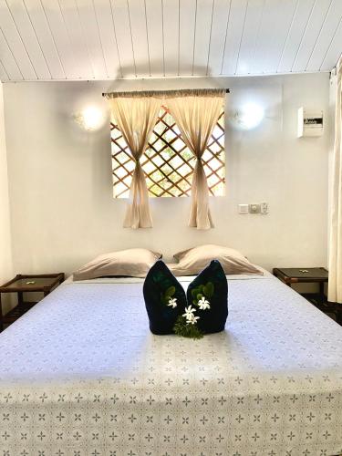 a bed with two black pillows with flowers on it at Poe Guesthouse in Avatoru