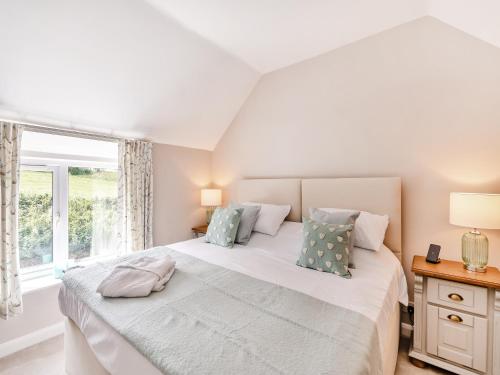 a bedroom with a large white bed with a window at Wheelwrights Cottage in Yeaveley