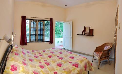 a bedroom with a bed and a chair and a window at Raintree Garden in Mysore