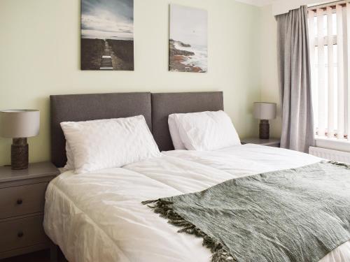 1 dormitorio con 1 cama con sábanas y almohadas blancas en Gwynfa, en Rhyl