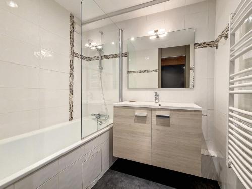 une salle de bain avec un lavabo, un miroir et une baignoire dans l'établissement Appartement spacieux avec balcon orienté Sud, au pied des pistes, proche La Croisette. - FR-1-344-1177, aux Menuires