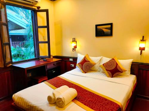 ein Hotelzimmer mit einem Bett und einem Fenster in der Unterkunft Lotus Corner - Vegan & Plant Based B&B in Luang Prabang