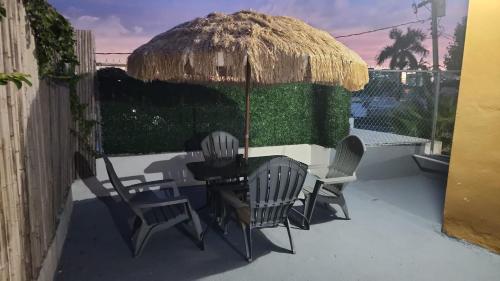 eine Terrasse mit Stühlen, einem Tisch und einem Strohschirm in der Unterkunft Home San Juan in San Juan