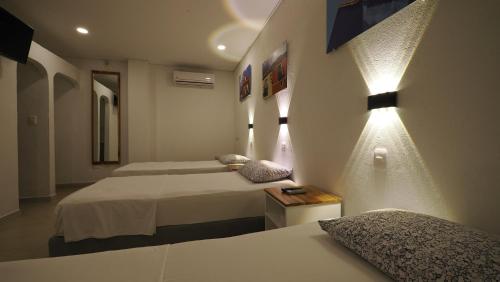 a hotel room with two beds and a light on the wall at Hotel Casa Cytia in Cartagena de Indias