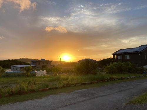 a sunset over a field with houses and a road at ＰＥＮＳＩＯＮ　ＳＨＩＭＡＫＡＺＥ in Motobu