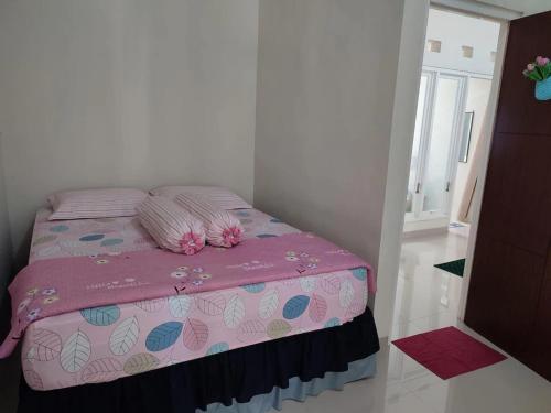 ein Schlafzimmer mit einem rosa Bett mit Kissen darauf in der Unterkunft Latasari 33A Homestay in Tuban