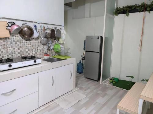 a kitchen with white cabinets and a stainless steel refrigerator at Latasari 33A Homestay in Tuban