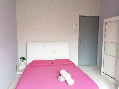 a bedroom with a pink bed with two towels on it at DKAMAR Homestay At Desaru, Fully Aircond, WiFi, Coway, Street View 4 min to Desaru Beach in Kangkar Chemaran