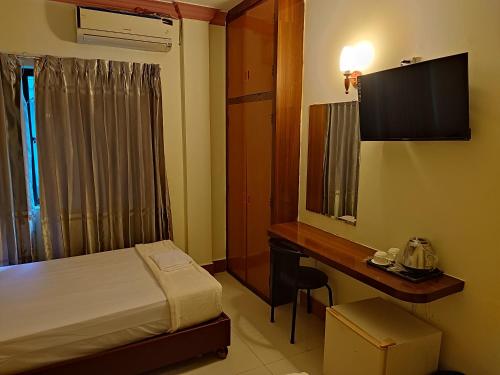 una camera con letto, scrivania e TV di GALAXY Rs HOTEL a Phnom Penh
