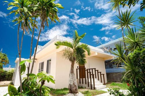 a white house with palm trees in front of it at NEWOPEN Villa lanikai in Kabira