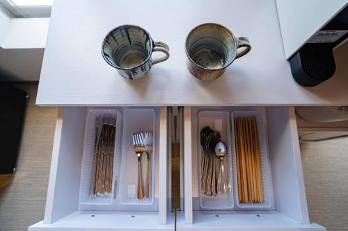 a white table with two cups and utensils at NEWOPEN Villa lanikai in Kabira