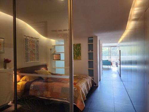 a bedroom with a bed and a glass wall at GREEN ROSE ~ Peaceful • Green • Haven in Canberra