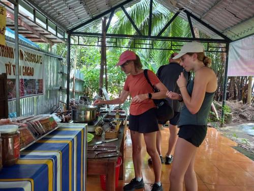 un grupo de personas de pie alrededor de un puesto de comida en Mecong Homestay en Ben Tre