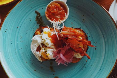 a blue plate with a sandwich with sauce on it at Namu Garden Hotel & Spa - Adults Only in Puerto Viejo