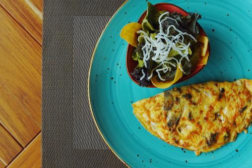 a blue plate topped with an omelet and a salad at Namu Garden Hotel & Spa - Adults Only in Puerto Viejo