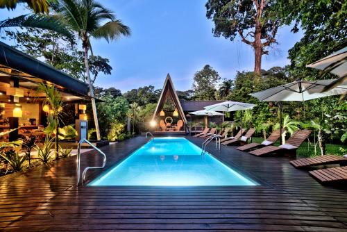 uma piscina num resort com cadeiras e guarda-sóis em Namu Garden Hotel & Spa em Puerto Viejo