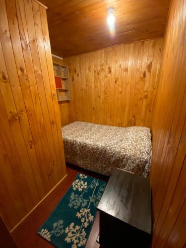 um pequeno quarto com uma cama num chalé de madeira em Hospedaje Pudahuel em Santiago