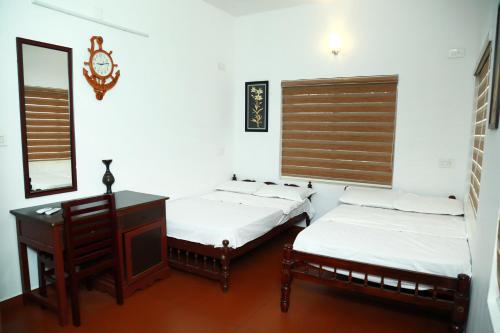 two beds in a room with a desk and a mirror at Back Packers Cochin Villa in Cochin