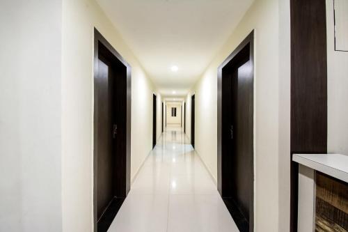 un pasillo de un hotel con puertas negras y suelos blancos en Hotel CJ Inn en Gunadala