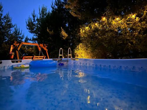 a swimming pool at night with a tractor in the background at Sodyba Vilagio in Alanta