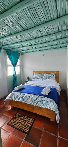 ein Schlafzimmer mit einem Bett mit blauer Decke in der Unterkunft PUEBLITO BOYACENSE - Hospedaje El Cocuy in Duitama