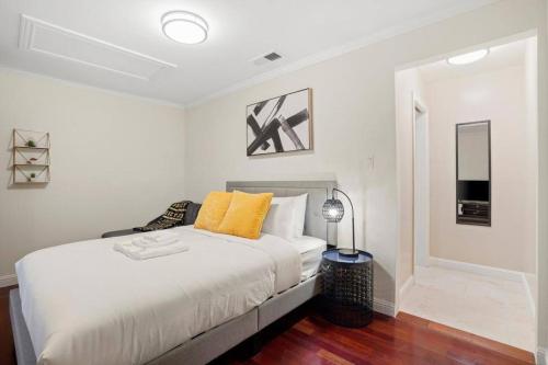 a white bedroom with a large bed with yellow pillows at Lovely Relaxing Private Studio Near Westlake in Daly City