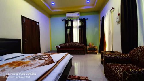 a bedroom with a bed and chairs in a room at Subansiri lodge in Majuli