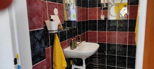 a bathroom with a sink and red and black tiles at AG Studio Apartment in Gabčíkovo in Gabčíkovo