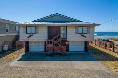 a house on the beach with the ocean in the background at Twin Coho in Rockaway Beach